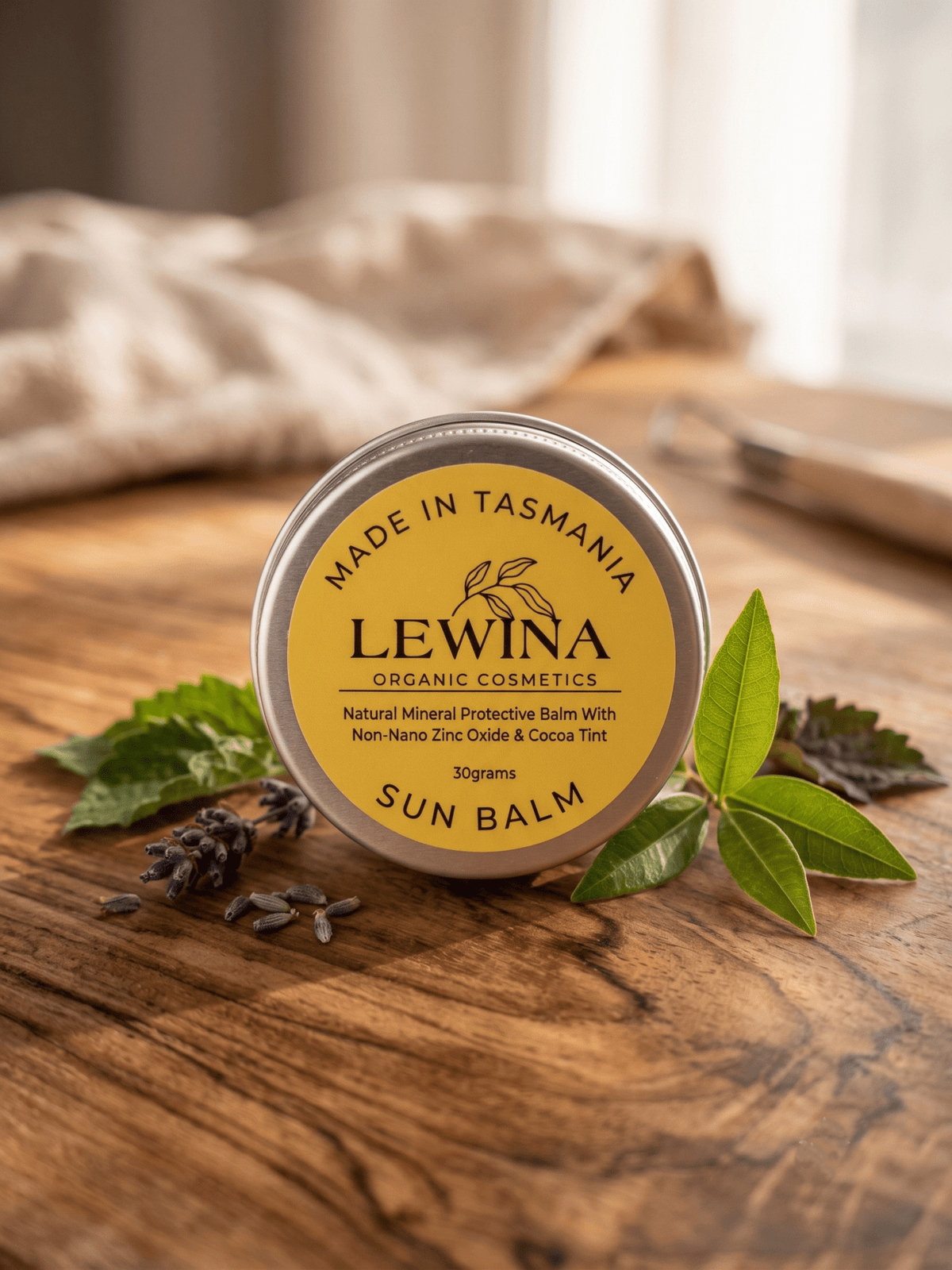 Lewina natural water-free Sun Balm tin on weathered timber with Tasmanian coastal garden styling