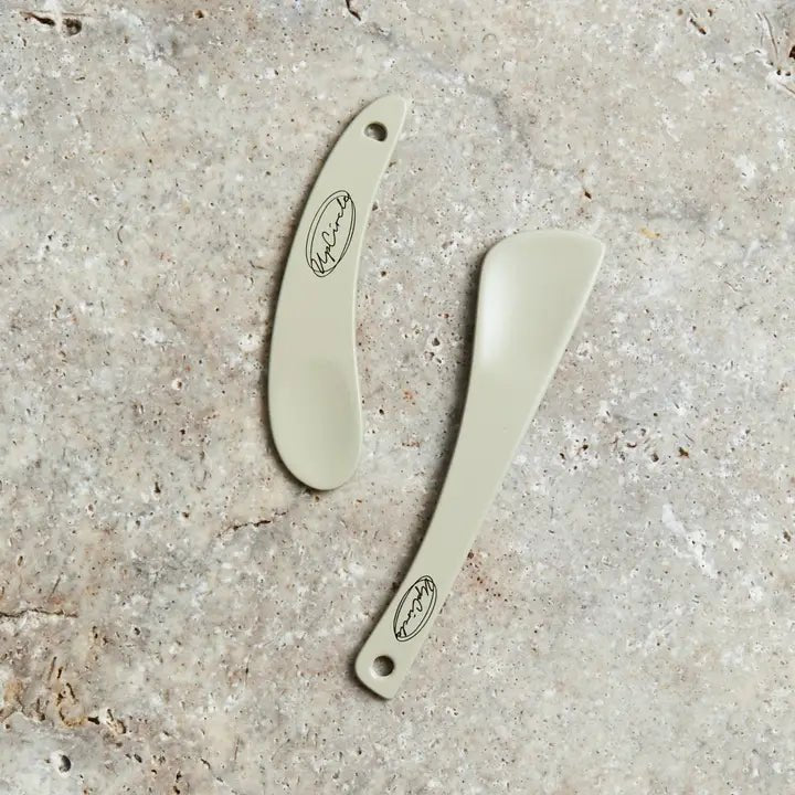 Two reusable cosmetic spatulas on a clean background.